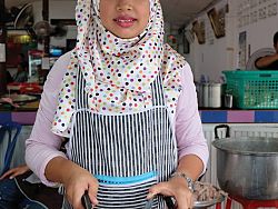 A young Muslim woman cuts up fried chicken at Gai Tod Decha