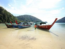 Longtails along a beach waiting for tourists to transport
