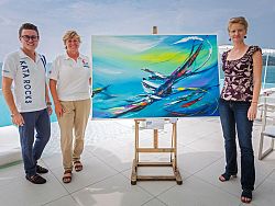 From left to right: Painting that raised THB 150,000 (US$ 4,500) forthe Phuket Youth Sailing Club (PYSC). From left to right: Tim Sargeant(Marketing and Events Manager, Kata Rocks), Katy Gooch from th